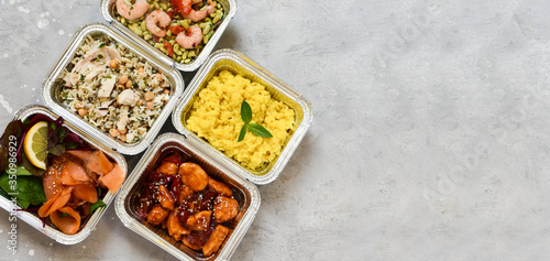 Food delivery. Different aluminium lunch box with healthy natural food risotto, chicken chickpeas and rice, salmon salad, hot chicken teriyaki, shrimp and green beans. airlines food. airline meals