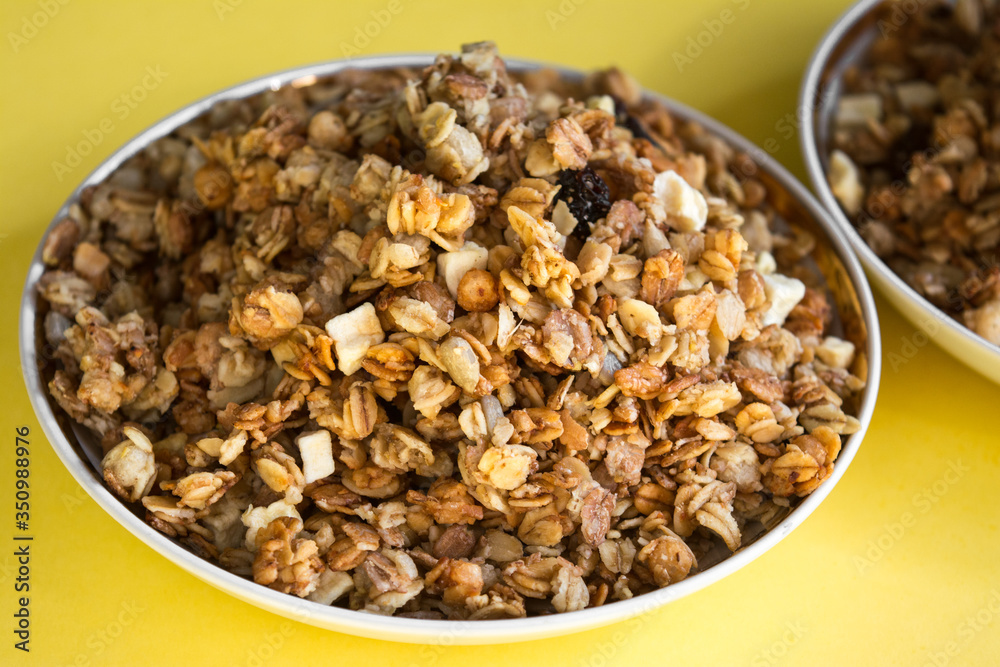 muesli fried cereals in a plate gold dried fruits raisins on a yellow background place for text muesli fried cereals in a plate gold dried fruits raisins on a yellow background place for text