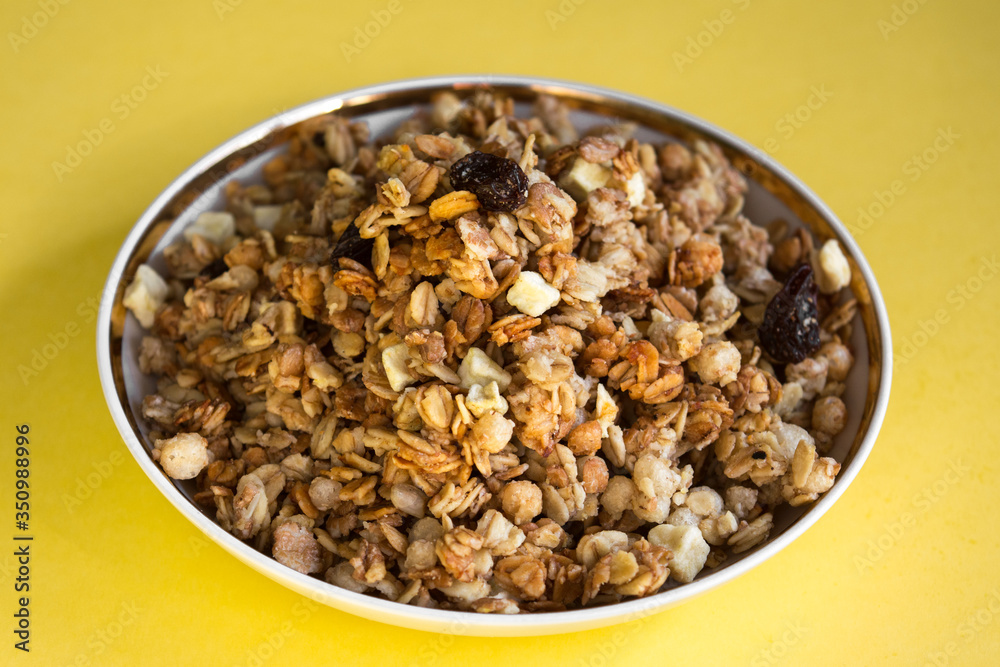 muesli fried cereals in a plate gold dried fruits raisins on a yellow background place for text muesli fried cereals in a plate gold dried fruits raisins on a yellow background place for text