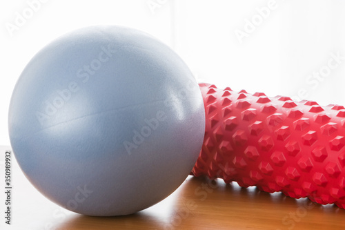 A blue pilates ball and a red fascial massage roller