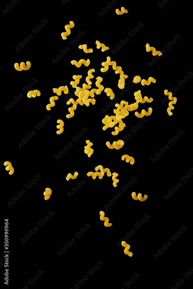 Italian flying raw pasta isolated on black background. macaroni cellentani falling.