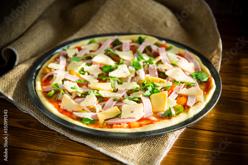 raw pizza with assorted filling in a metal form