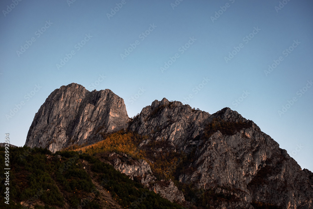 Limestone rock mountain with autumn pine forest and blue sky