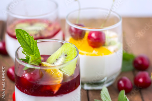 three types of milk jelly Panna cotta in glass glasses decorated with fresh fruit