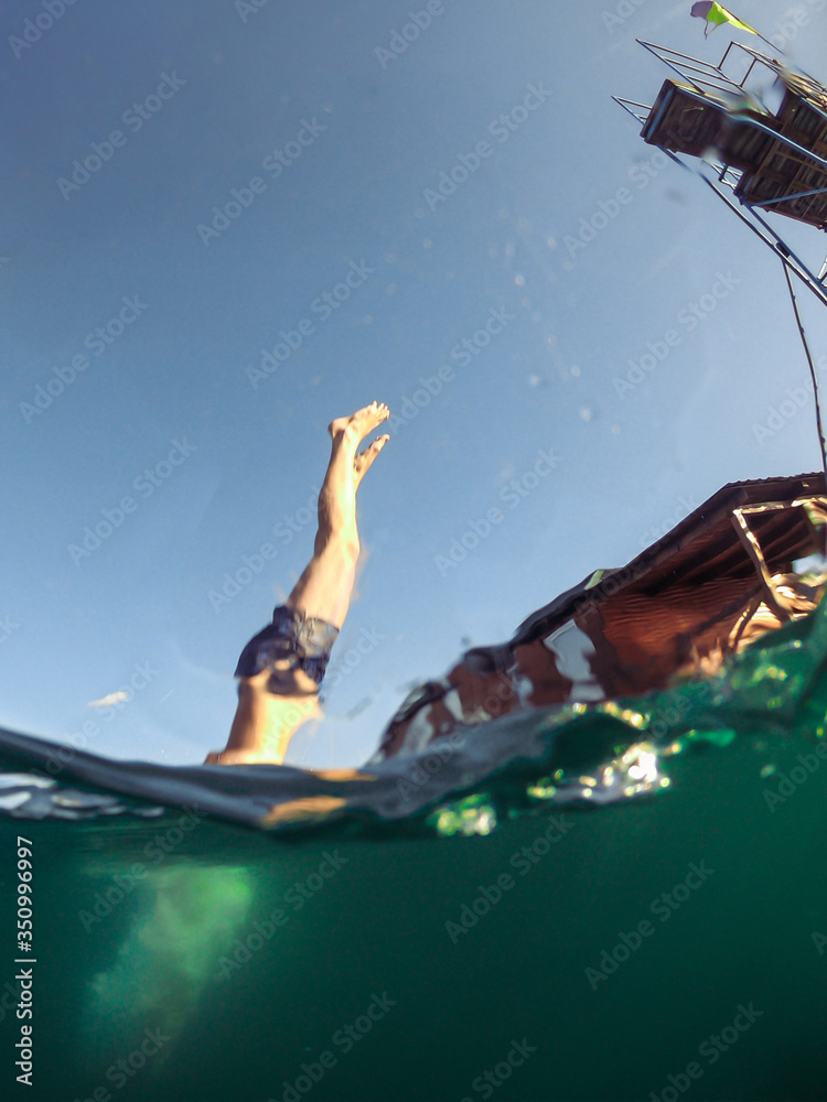 Naklejka premium man jumping from tower to lake water