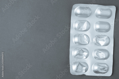 Pills in open blister pack on dark background with copyspace.