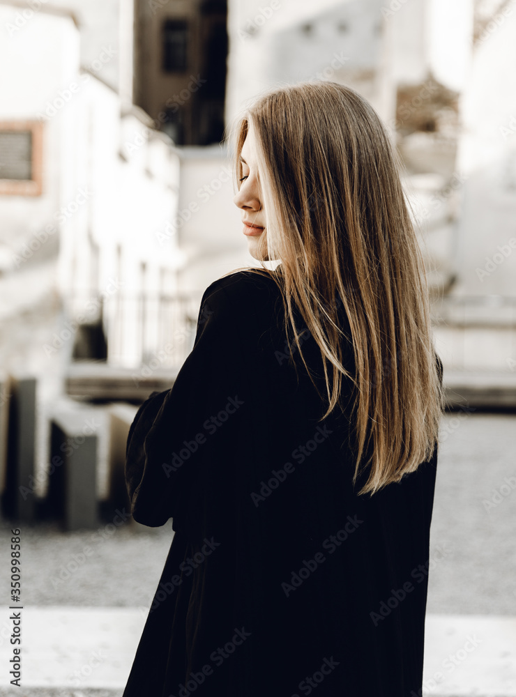 a beautiful young girl in a black dress with chic shiny hair posing and smiling at the camera; the girl waves her hair; dreamy mood a beautiful young girl in a black dress with chic shiny hair posing and smiling at the camera; the girl waves her hair; dreamy mood
