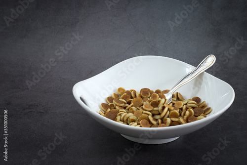 Pancake cereal. Trendy food, mini cereal pancakes in bowl on the table, grey cement background. Trendy baked mini pancakes with strawberries, blueberries . Copy space. Flat layout. Table top view. © rasa