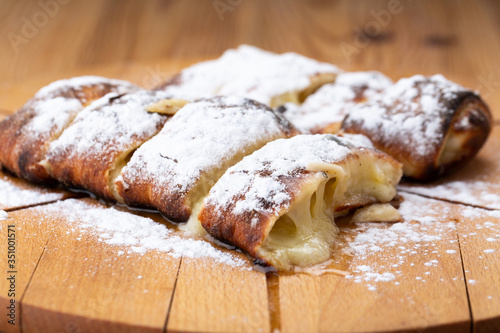 fruit strudel on a wooden board sprinkled with icing sugar. delicious pastries