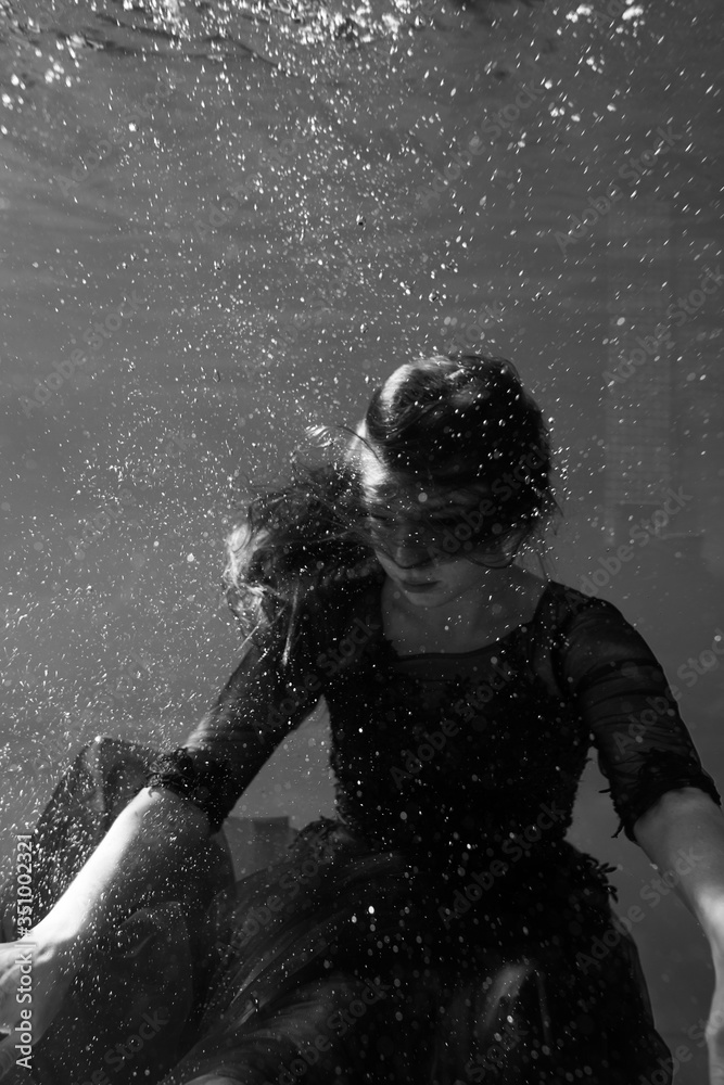 Black and white photo. Beautiful girl underwater in a red dress swims in the pool. Tenderness and elegance. Bubbles and a lot of water Black and white photo. Beautiful girl underwater in a red dress swims in the pool. Tenderness and elegance. Bubbles and a lot of water