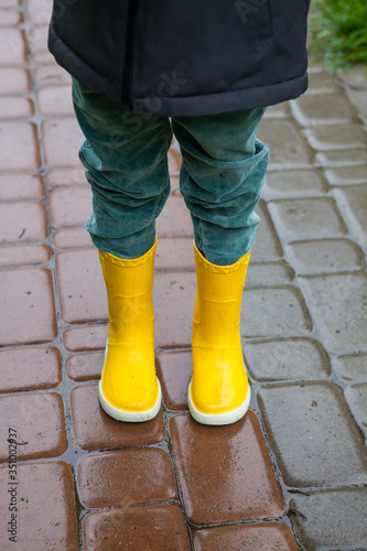 Boy in yellow boots in the rain