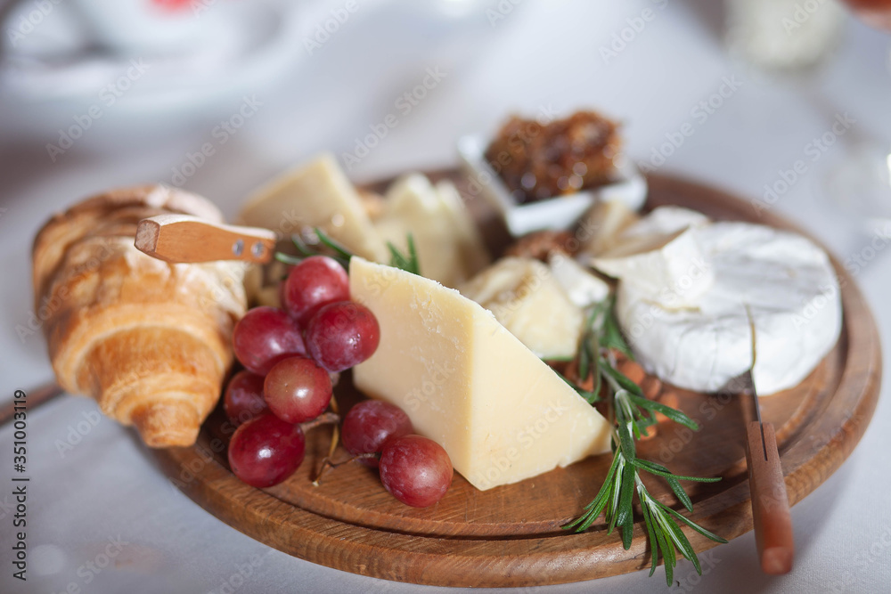 cheese croissant and grapes on a wooden plate