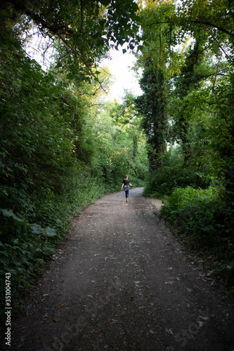 Girl walking through the dense forest, along gravel pathway