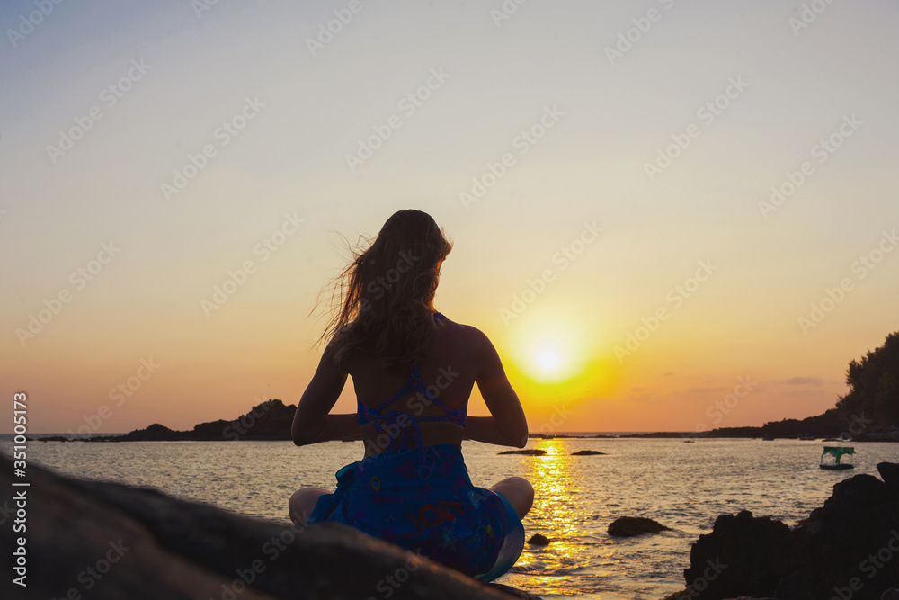a beautiful woman meditates on a rock
