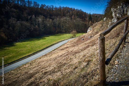 The path climbs up towards the rocks and the road runs through the valley