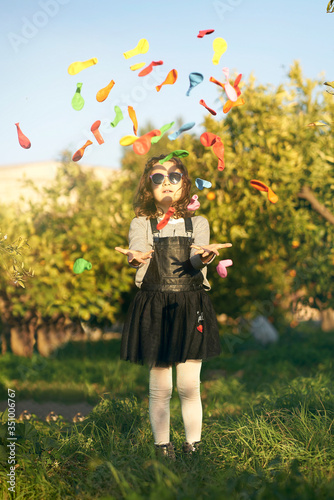 Happy little girl playing with colorful toy balloons outdoors.