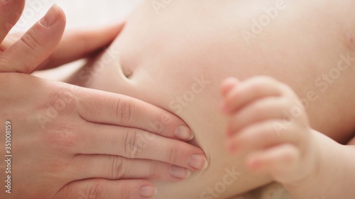 Mother massaging baby tummy. Baby skin care and development concept.