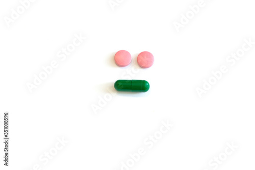 Colored round pills on a white background with copy space in the form of a smiley
