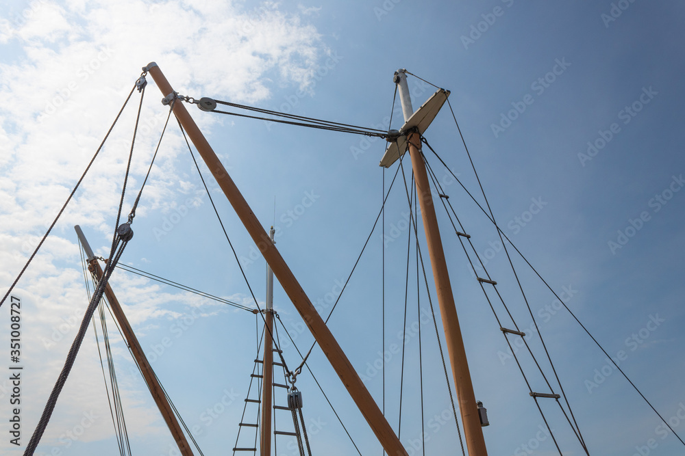 Masts with rigging, block and tackle, old sailing vessels silhouetted against a blue sky, horizontal aspect Masts with rigging, block and tackle, old sailing vessels silhouetted against a blue sky, horizontal aspect