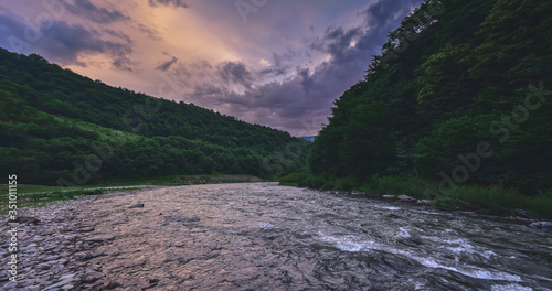 Foto Fabulous amazing sunset under fast stream river in the mountain landscape