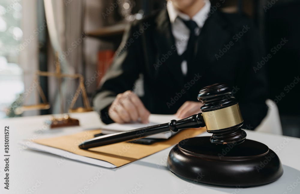 Justice and law concept.Male judge in a courtroom with the gavel, working with, computer and docking keyboard, eyeglasses, on table in morning light Justice and law concept.Male judge in a courtroom with the gavel, working with, computer and docking keyboard, eyeglasses, on table in morning light