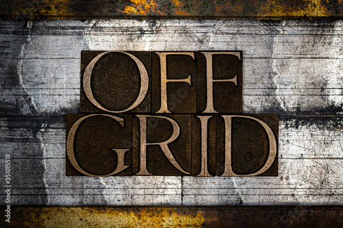 Photo of real authentic typeset letters forming Off Grid text on vintage textured grunge silver and gold background
