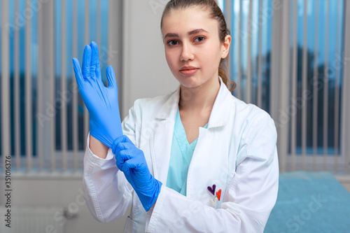 Doctor's hands putting on latex gloves in a hospital. Woman in a doctor's smock in latex gloves. Protection against virus and bacteria. Kovid 19. Health photo