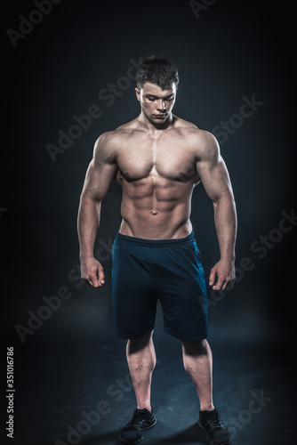 Sexy young athlete posing on a black background in the Studio. Fitness, bodybuilding