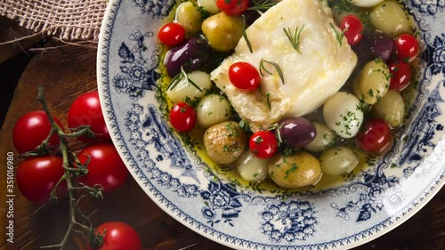 Slide shot Portuguese dish with codfish called Bacalhau do Porto in a original portuguese plate. Top view with smoke.