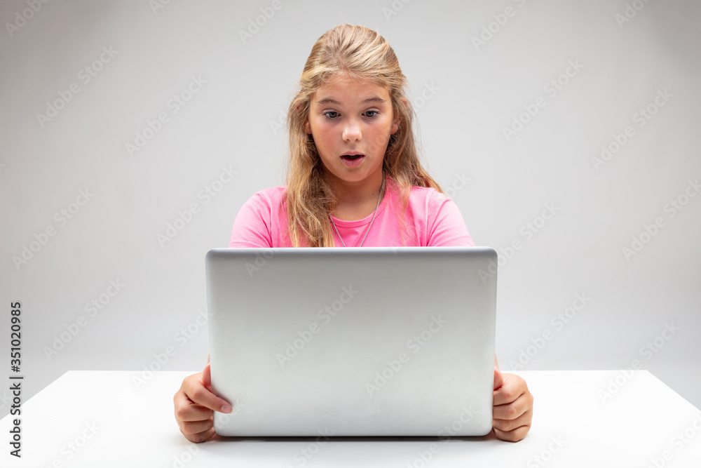 Little girl staring at her laptop in astonishment Little girl staring at her laptop in astonishment