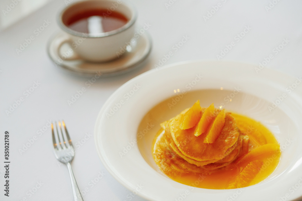 Pancake with orange on a white plate and tea Pancake with orange on a white plate and tea