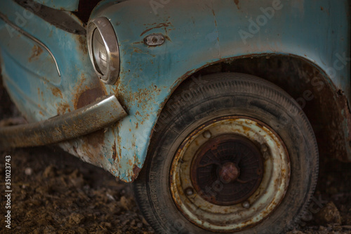 an old rusty car with a fallen off bumper