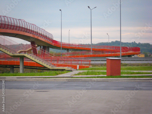 Pedestrian bridge with red railing over a highway.