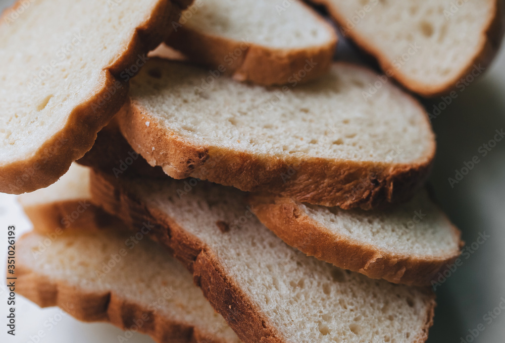 Scattered pieces of white dried bread lie on a white background. Photography, concept.