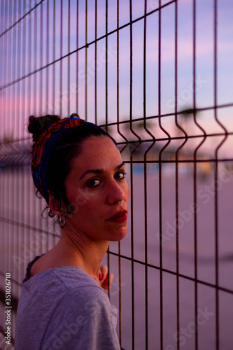 Mujer apoyada en una alambrada al atardecer