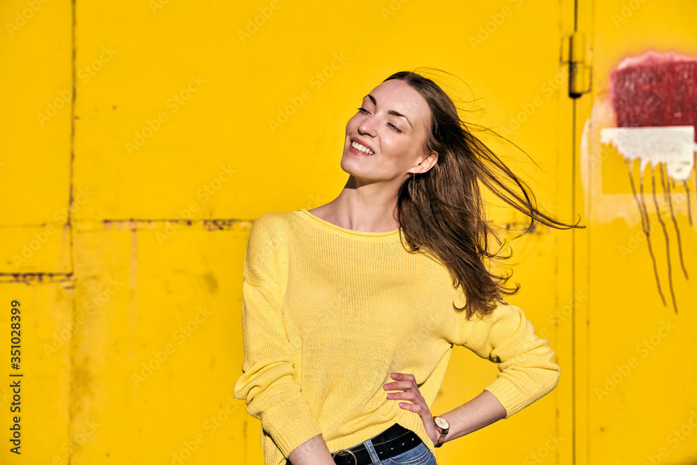 Smiling girl in yellow jacket stands against a yellow wall Smiling girl in yellow jacket stands against a yellow wall