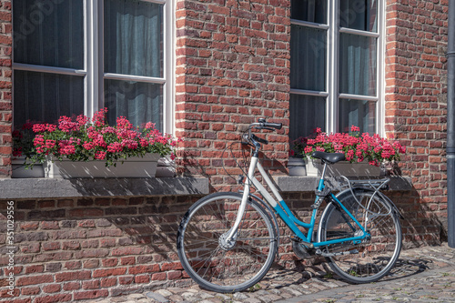 The typical Flemish view of the bicycle near old stone house © Evgeny