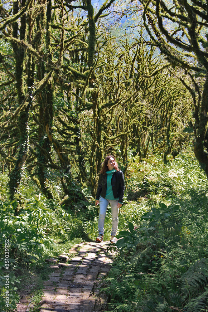 photo of a girl, walking along the trail path, through Dead boxwood forest to Mirveti Waterfall in the mountains of Georgia at sunny day, in spring. photo of a girl, walking along the trail path, through Dead boxwood forest to Mirveti Waterfall in the mountains of Georgia at sunny day, in spring.