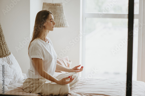 Young woman practicing meditation on bed.