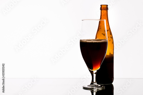 A glass of beer and a bottle on the mirror table