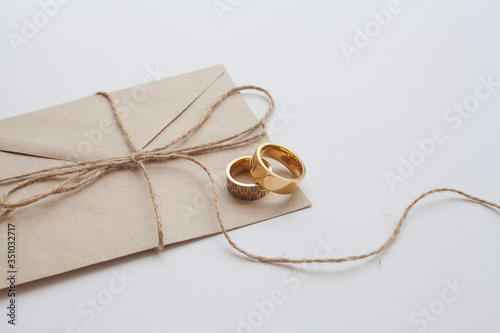 Wedding rings on a white background are decorated with an invitation envelope. Concept photo for a wedding.