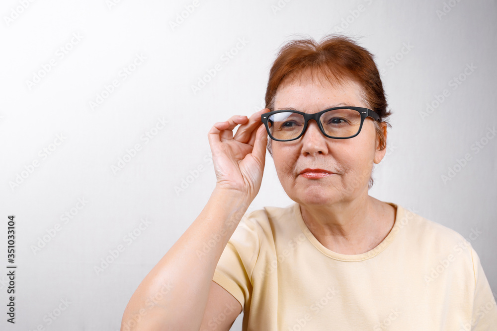 senior woman looks away with glasses on a white background in a light T-shirt. place for text, isolated senior woman looks away with glasses on a white background in a light T-shirt. place for text, isolated