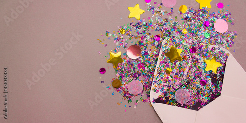 Banner with opened white envelope with multicolored sparkle glitter confetti letters on pastel lilac background. Festive greeting concept. Flat lay style. Top view. Place for text