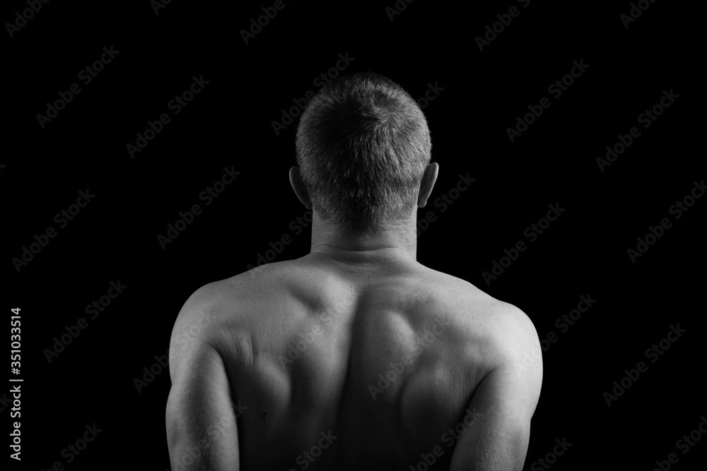 Male model athlete with muscular sexy body and bare back. Man's back and hands on a black background. Pumped back and arms. Male model athlete with muscular sexy body and bare back. Man's back and hands on a black background. Pumped back and arms.