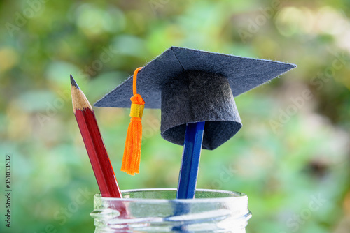Global education success / graduate study aborad program concept : Black graduation cap or a mortarboard, blue and red pencils in a bottle, depicts achievement in higher mba learning course in academy photo