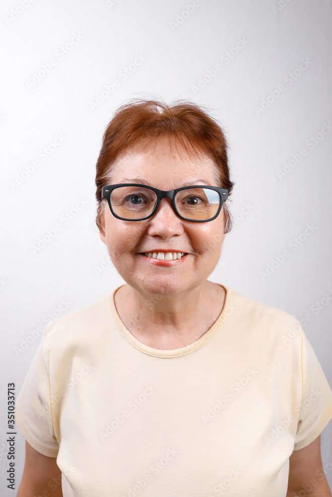 happy senior woman with glasses on a white background in a light T-shirt. place for text, isolated