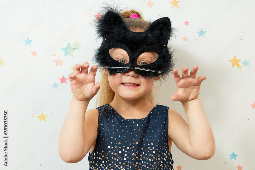 Happy Halloween 2021. Little girl child in black cat mask, carnival costume. Funny face Happy Halloween 2021. Little girl child in black cat mask, carnival costume. Funny face