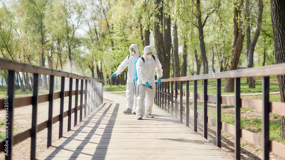 No spreading germs. Sanitization, cleaning and disinfection of the city park due to the emergence of the Covid19 virus. Specialized team in protective suits and masks at work No spreading germs. Sanitization, cleaning and disinfection of the city park due to the emergence of the Covid19 virus. Specialized team in protective suits and masks at work