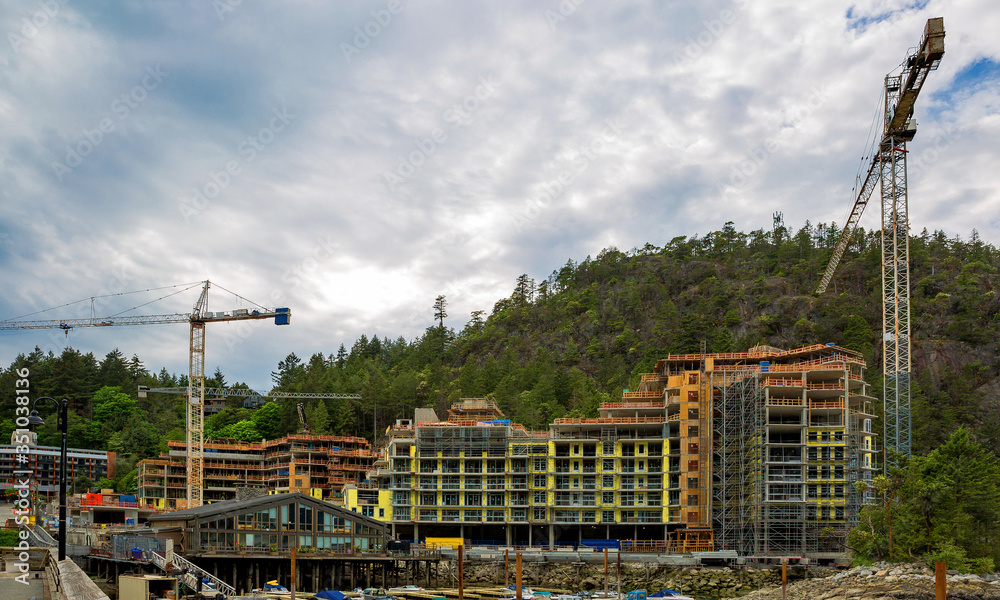 Construction of a new hotel complex in a recreation area on the shores of Horse Horseshoe Bay at the foot of an overgrown mountainside in West Vancouver, British Columbia, Canada