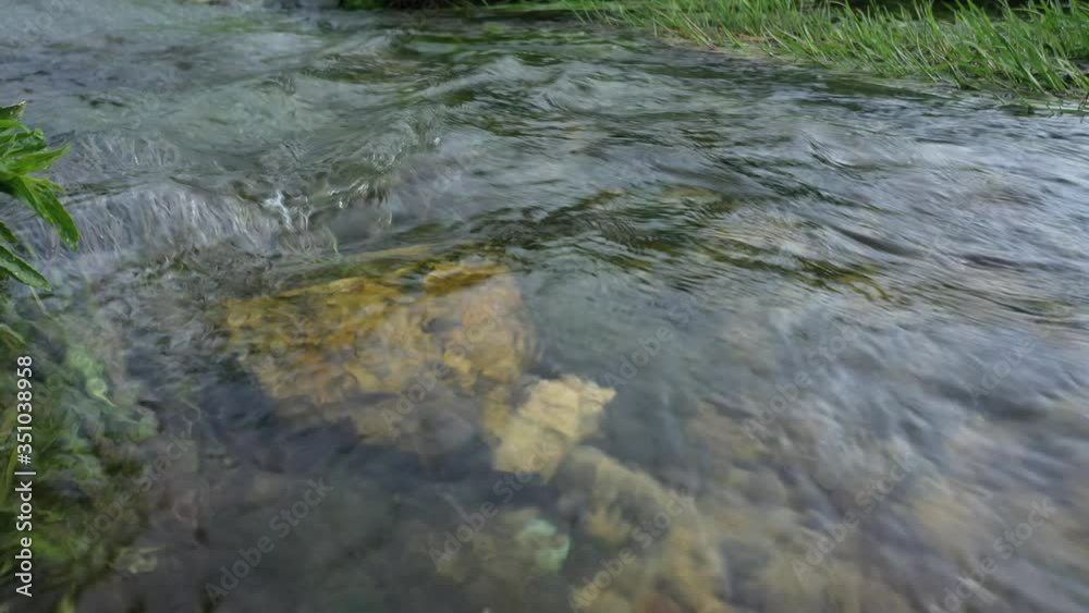 clear and clear spring water runs in a rapid stream along the rocky bottom clear and clear spring water runs in a rapid stream along the rocky bottom